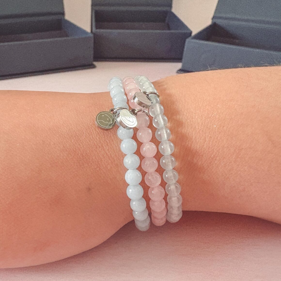 Otterspirit Crystal Bracelets on daughters wrist, lying flat with boxes in the background Feature Image.